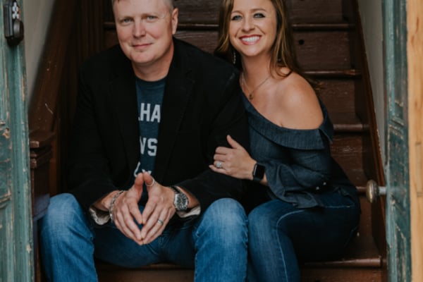 Couple sitting together on wooden staircase, both wearing jeans and casual tops